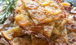 Schiacciata di patate croccante, dorata e invitante, con fette sottili di patate e un tocco di rosmarino.