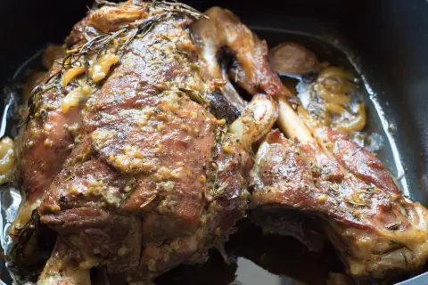Un succulento agnello al forno, dorato e profumato con rosmarino e aglio, pronto per essere gustato.