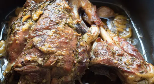 Un succulento agnello al forno, dorato e profumato con rosmarino e aglio, pronto per essere gustato.