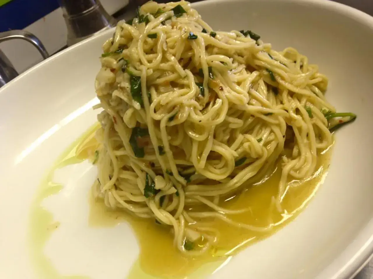 Un piatto di spaghetti aglio olio e peperoncino cremosi, conditi con prezzemolo fresco e un filo d'olio d'oliva.