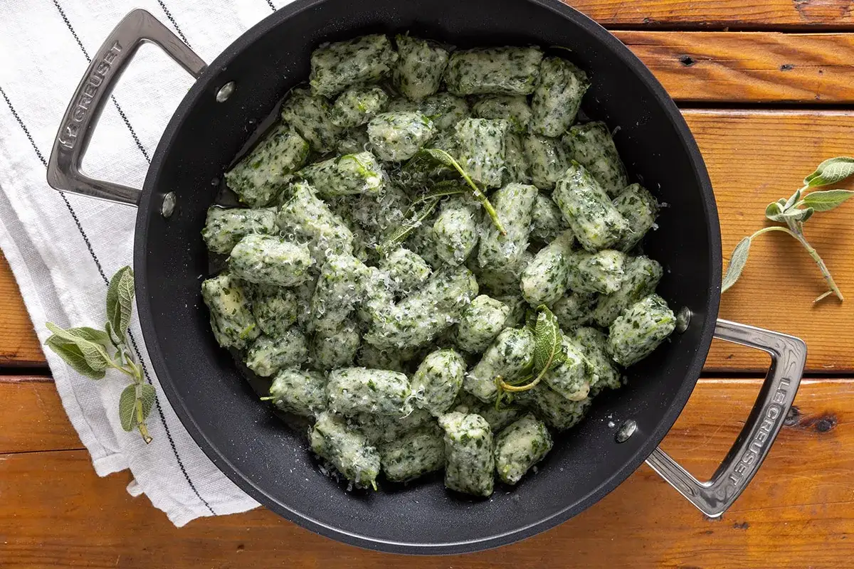 Strangolapreti alla trentina in padella, conditi con parmigiano e salvia fresca. Un piatto tradizionale pronto per essere gustato.