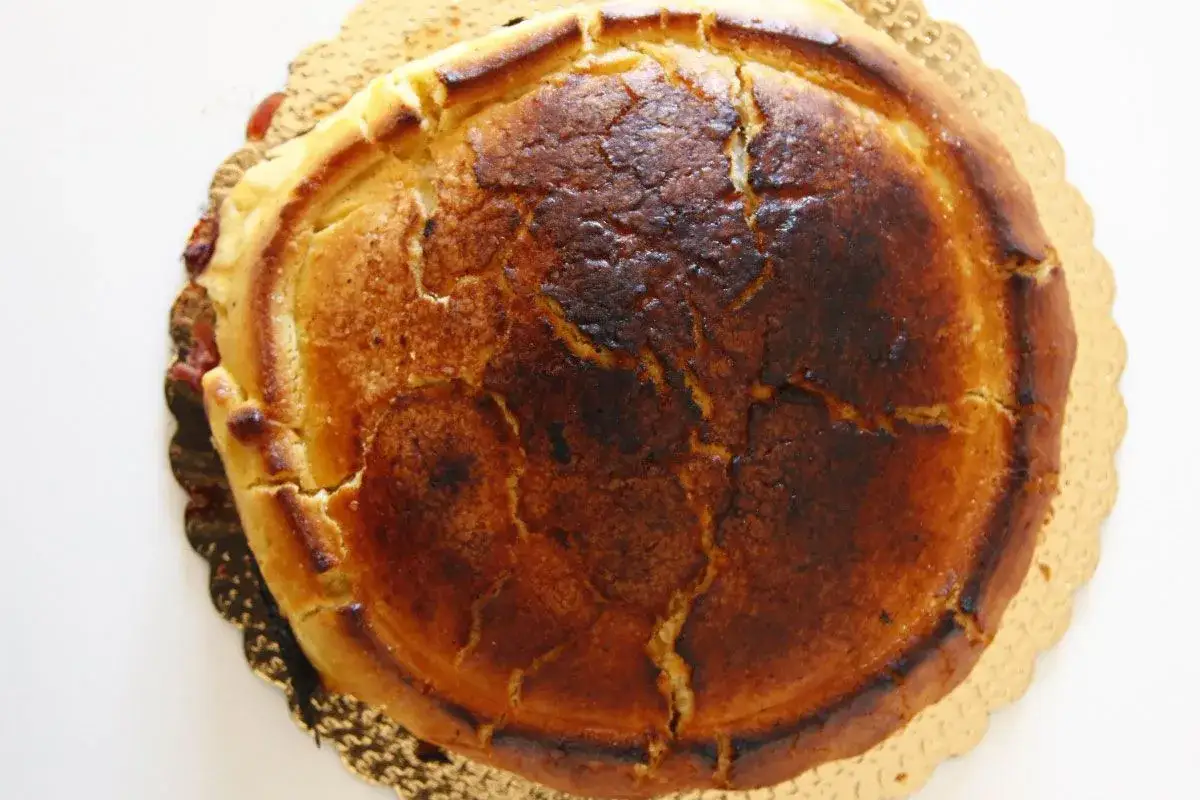 Crostata ricotta e visciole dorata e leggermente bruciacchiata, con un ripieno invitante che traspare dai bordi.