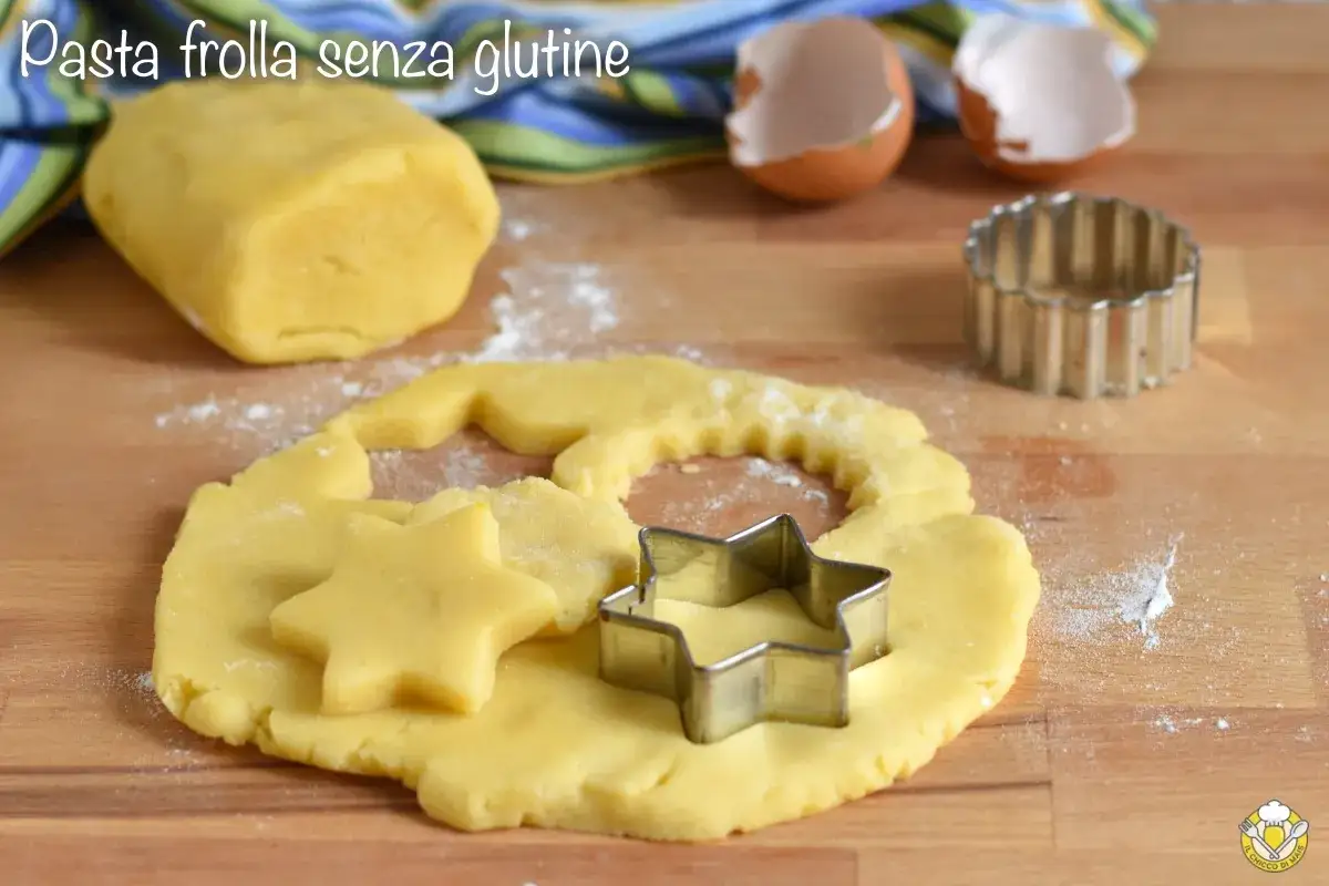Impasto giallo per pasta frolla senza glutine, con formine a stella e un rotella per biscotti.