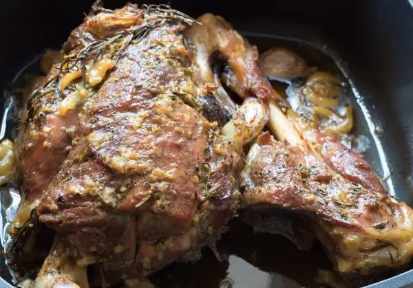 Un succulento agnello al forno, dorato e profumato con rosmarino e aglio, pronto per essere gustato.